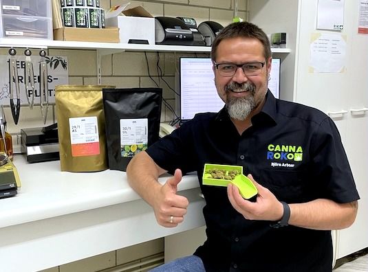 Apotheker Björn Arbter mit Medizinalcannabis-Blüten und CannaRoKo-Verpackungen im Cannabis-Bereich der Apotheke