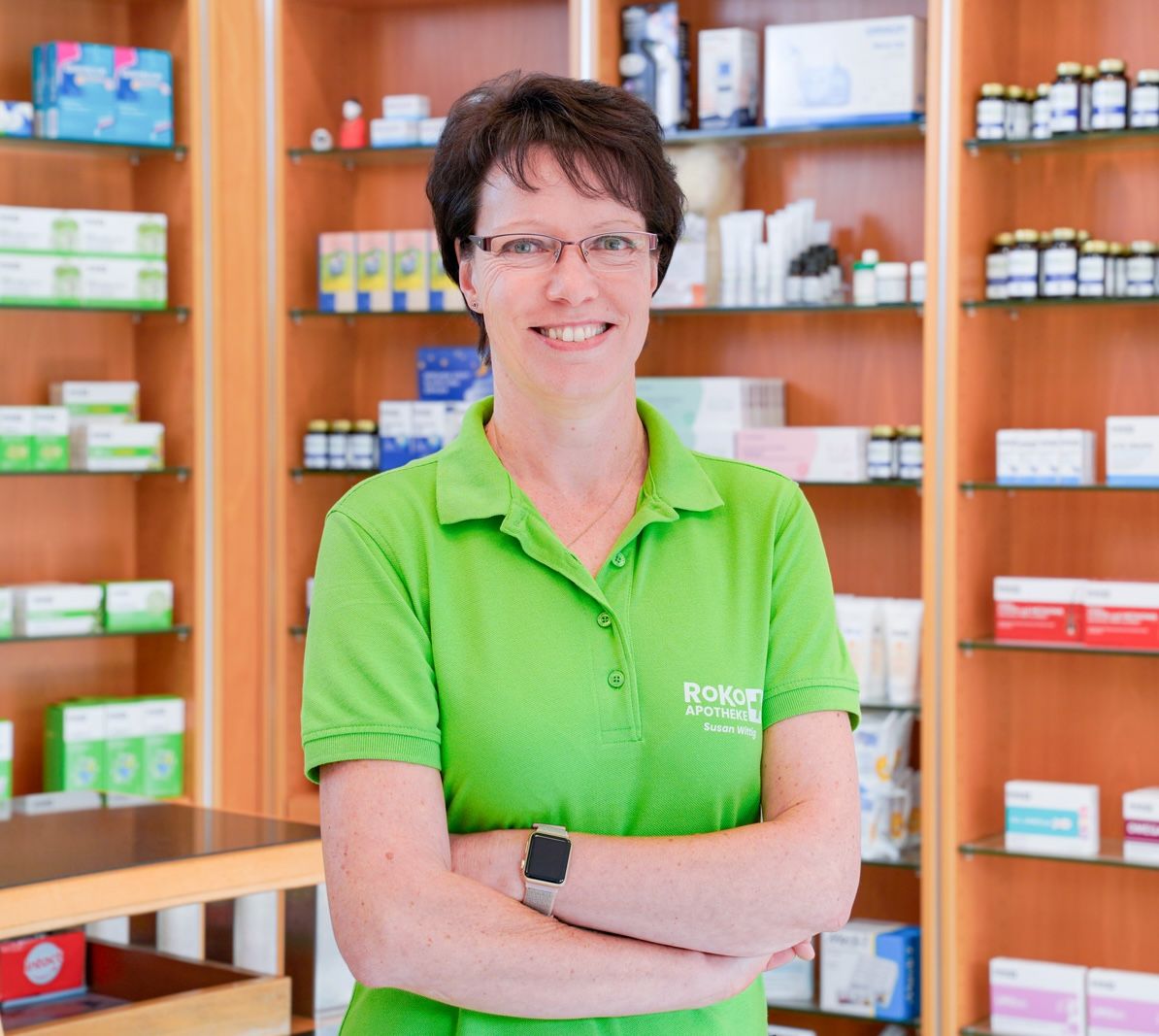 PTA der RoKo-Apotheken im grünen Poloshirt vor gefüllten Regalen