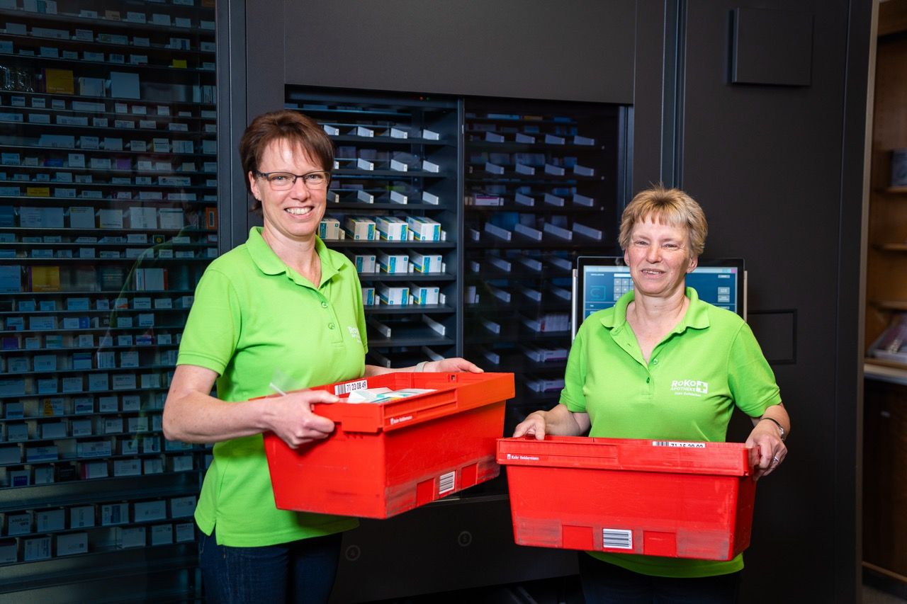 Zwei Mitarbeiterinnen mit roten Boxen in der Hand